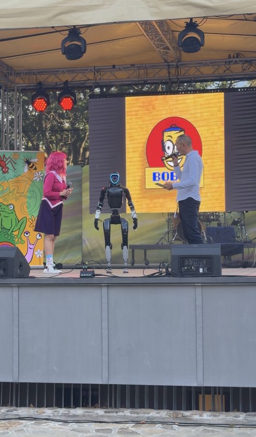 Unitree G1 humanoid robot on the stage of a children's festival next to the presenter